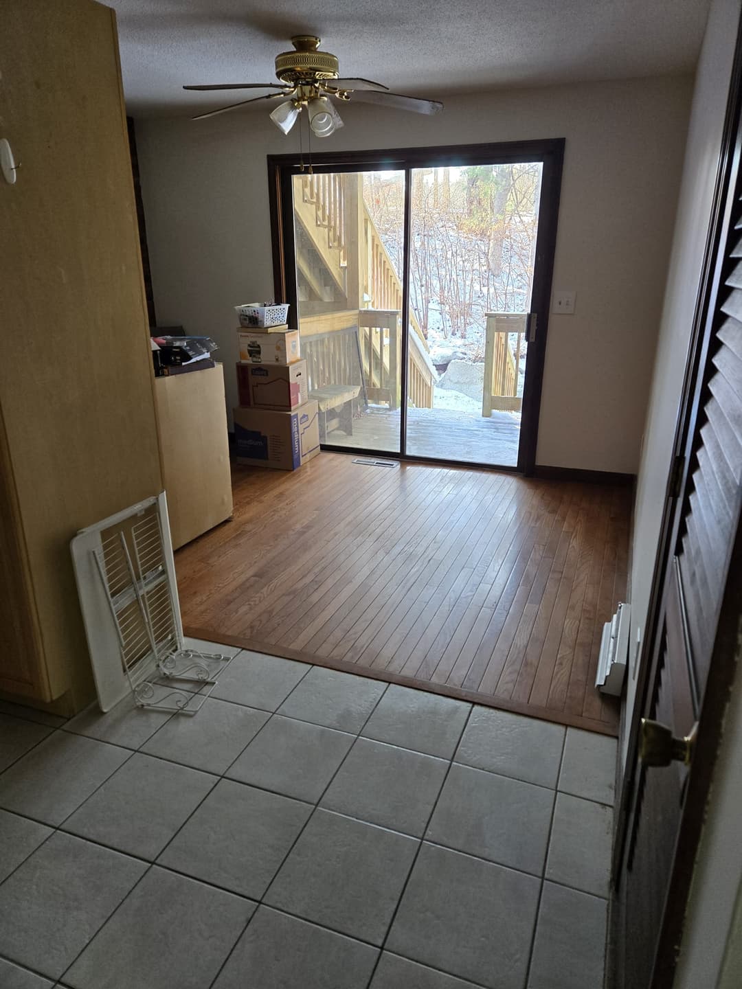 Entrance area with tile floor, sliding glass door, and wooden staircase in the background.