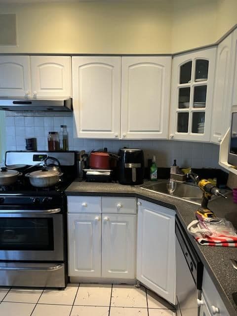 Modern kitchen with white cabinetry, stainless steel stove, and black countertops.