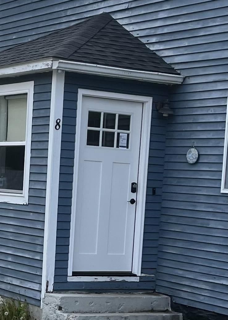 White front door with glass panel on blue house exterior, house number 8 visible.