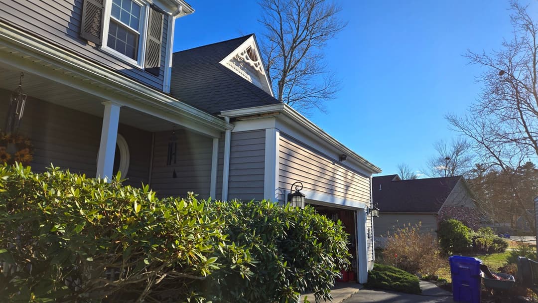 Exterior view of a modern home with landscaped bushes and clear blue sky.