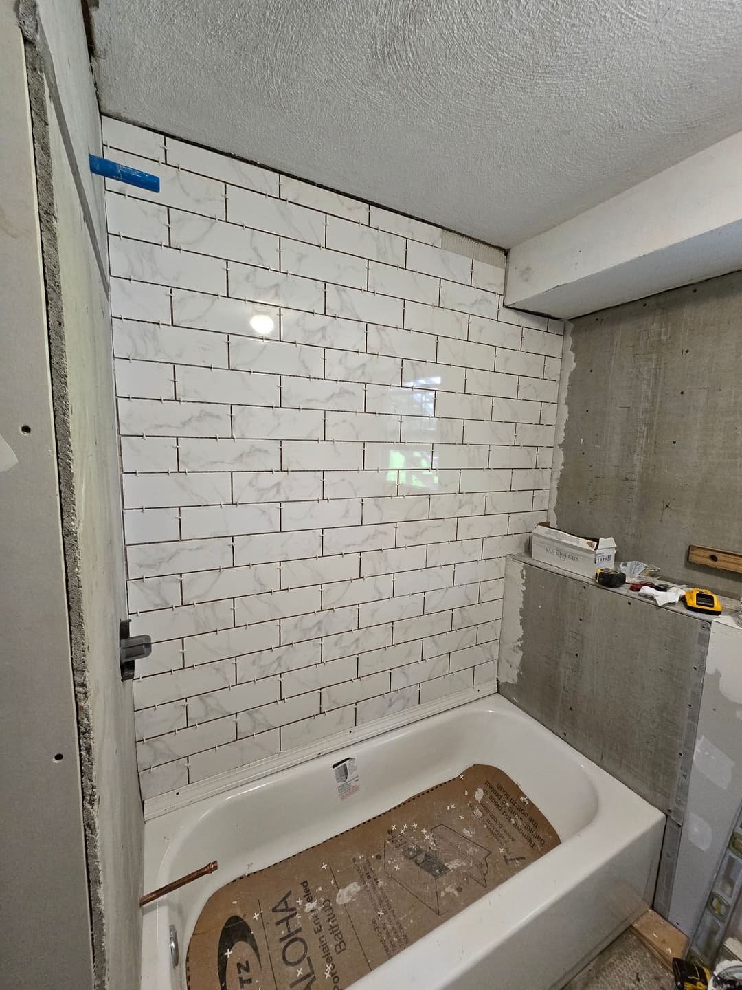 Bathroom renovation featuring white subway tile and a bathtub under construction.